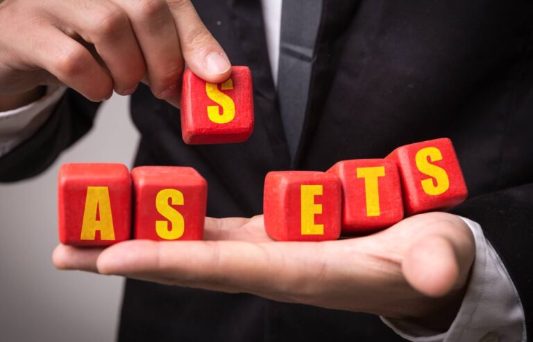 Business man holding blocks which spell out the word assets